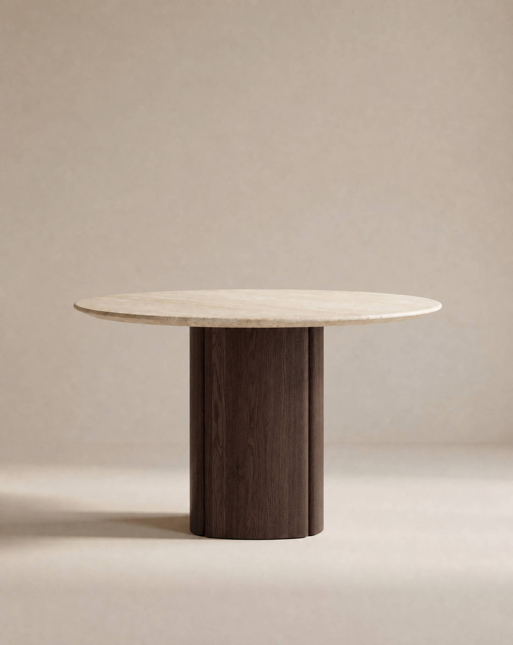 The Tathra Round Dining Table by Wooden Stories features a light stone top and a cylindrical dark solid oak base, shown against a plain beige background.