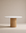 The Tathra Round Dining Table by Wooden Stories features a stone top and cylindrical solid oak base, showcased against a neutral beige background.