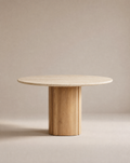 The Tathra Round Dining Table by Wooden Stories features a stone top, a thick cylindrical base, and minimalist design set against a beige background—perfect as a contract grade piece for versatile spaces.