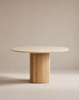 The Tathra Round Dining Table by Wooden Stories features a stone top, a thick cylindrical base, and minimalist design set against a beige background—perfect as a contract grade piece for versatile spaces.