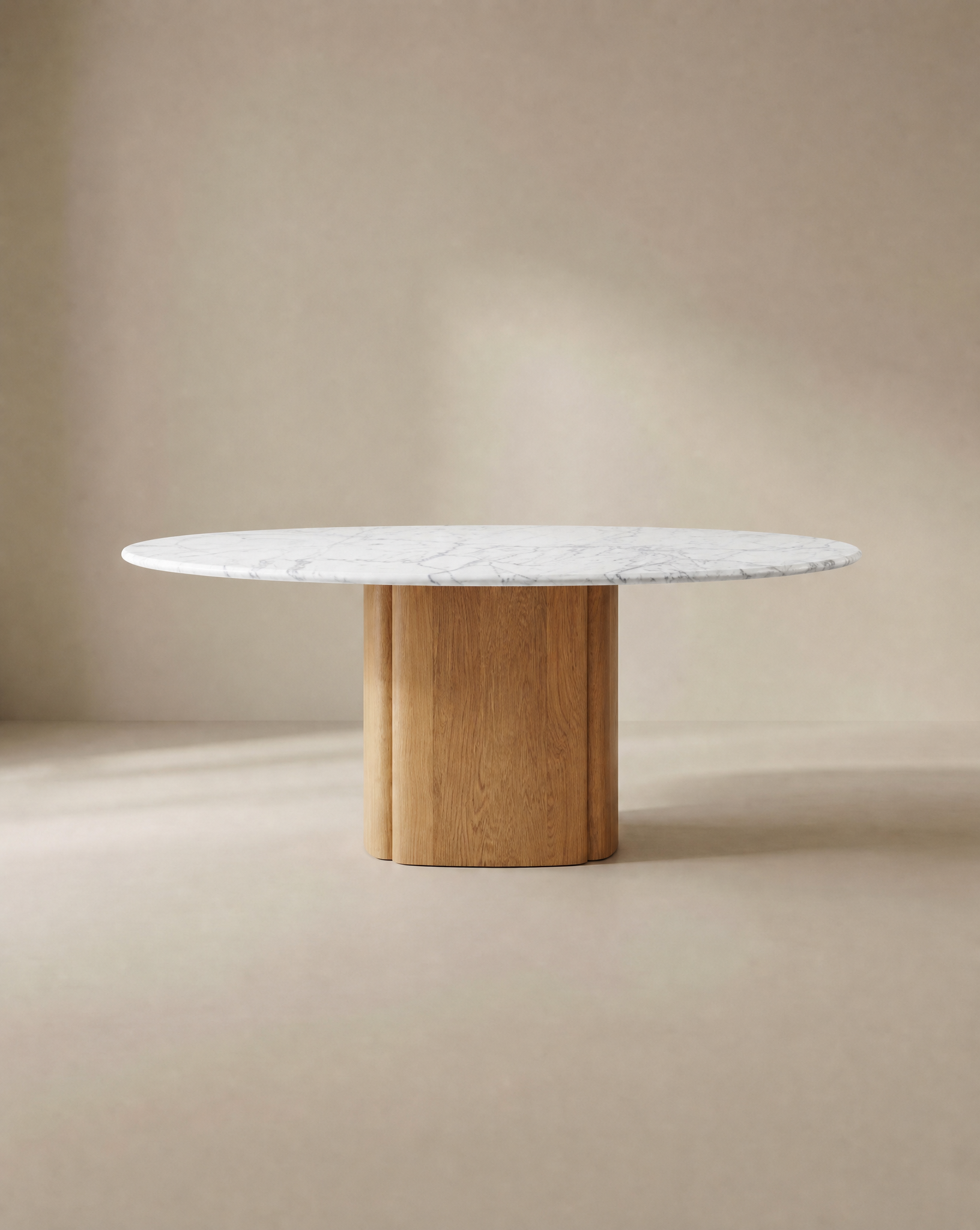 The Tathra Round Dining Table by Wooden Stories features a stone top and a cylindrical solid oak base, shown here with a white marble finish against a neutral beige background.