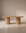 The Wooden Stories Tathra Ellipse Dining Table | Oak features a minimalist solid oak design with a smooth oval top and two cylindrical pedestal legs, elegantly situated in a softly lit, neutral-toned room.
