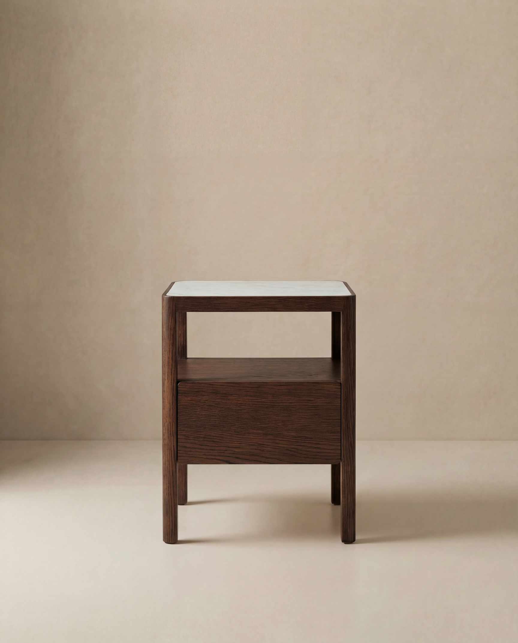 The Theo Nightstand by Wooden Stories features a minimalist, contemporary design with Danish-inspired lines, a rectangular white tabletop, open shelf, and single drawer, shown against a neutral beige background.