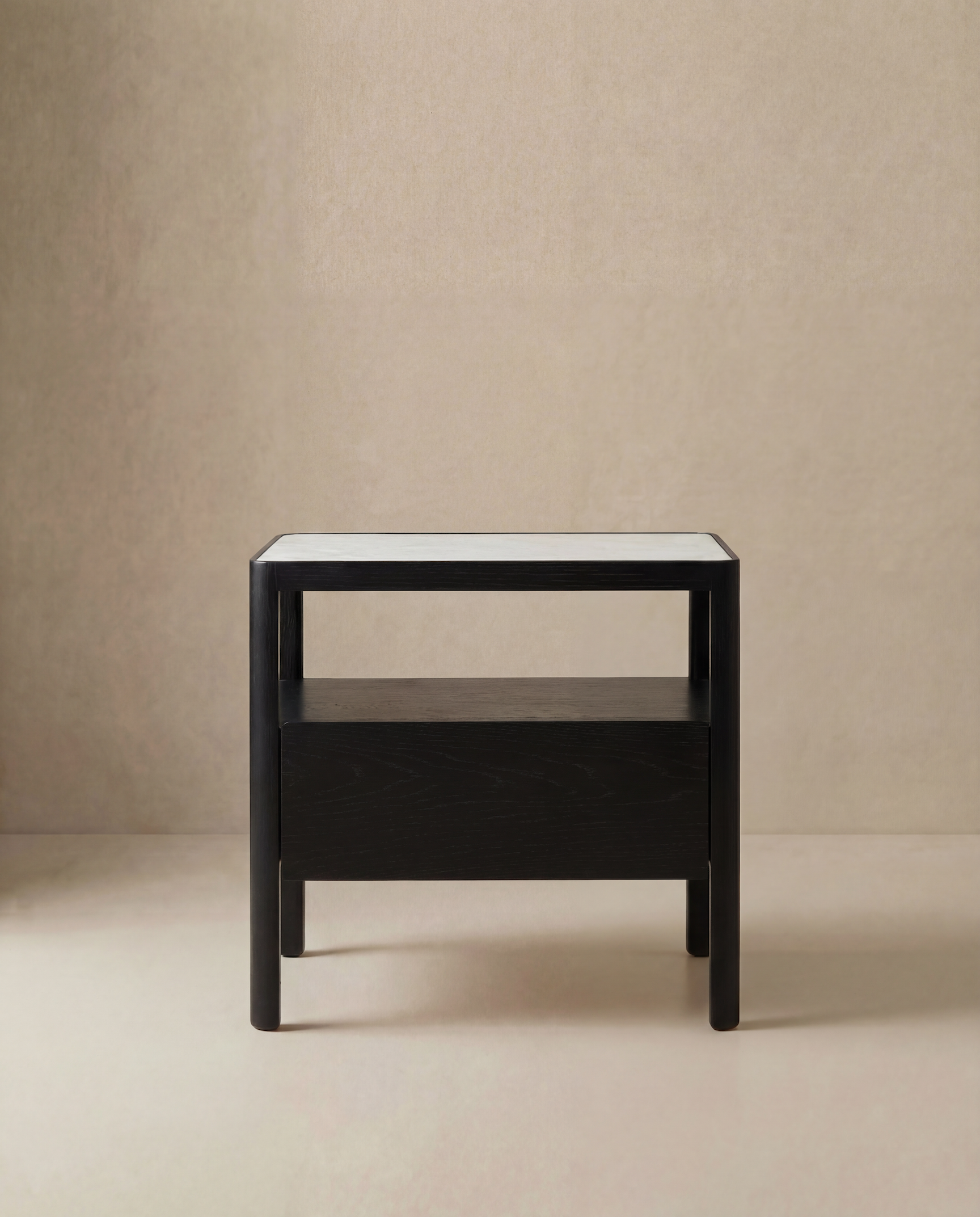 The Theo Nightstand Wide by Wooden Stories is a modern, minimalist black piece featuring Danish lines, a white tabletop, an open shelf, and a lower drawer, showcased against a plain beige background.