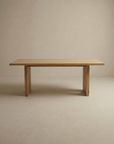 The Tommaso Dining Table by SOBU features a rectangular solid wood top, clean lines, and two sturdy wood legs, designed for durability and shown against a plain light beige background.