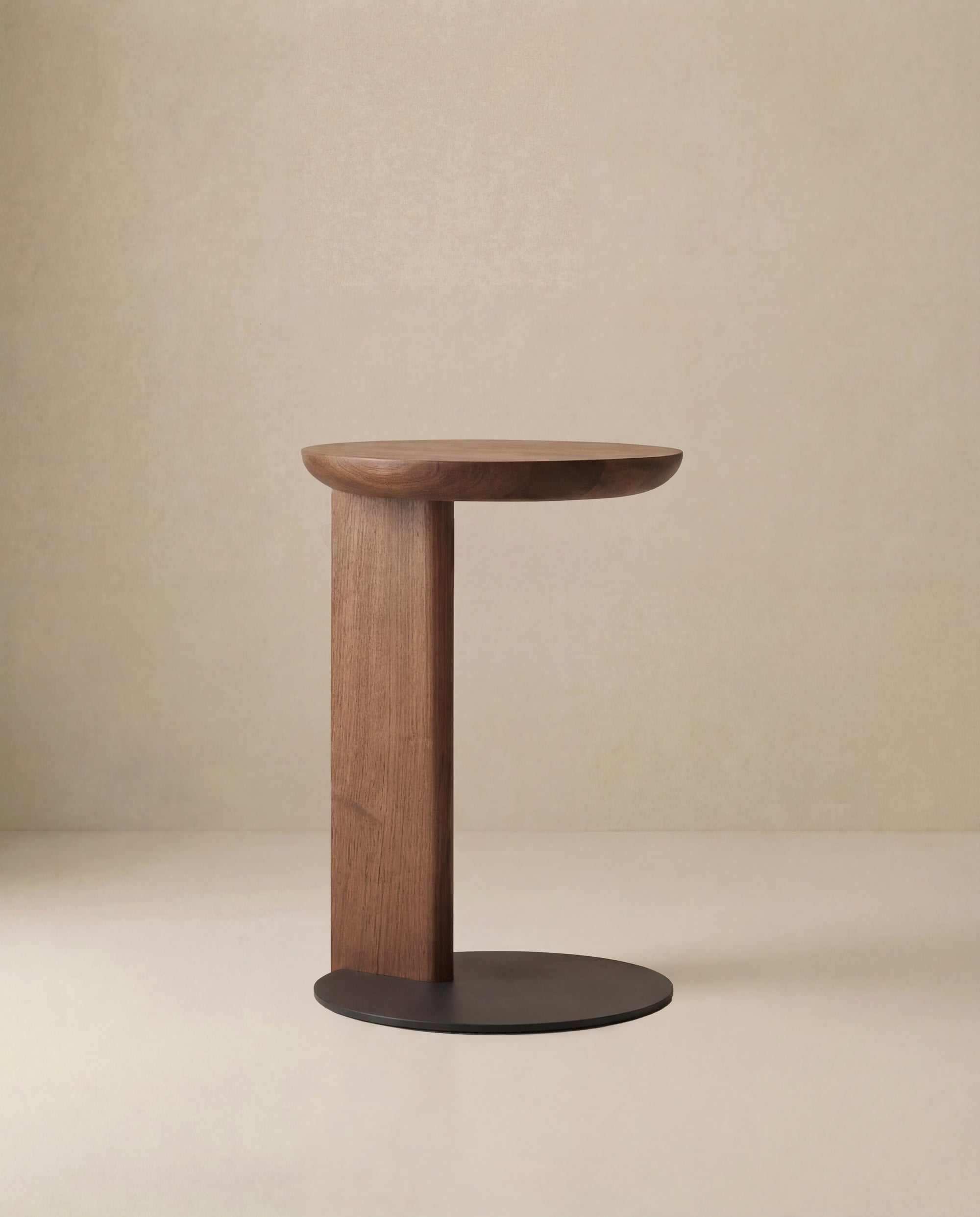 The Wooden Stories Guild Side Table features a modern, minimalist design with a round solid oak top, single vertical wooden support, and flat circular black base, displayed against a neutral beige background.