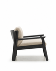 The Wren Lounge Chair | Fabric by Wooden Stories is a modern armchair inspired by Danish design, featuring a black wooden frame and light beige fabric cushions, shown in a side view against a plain white background.