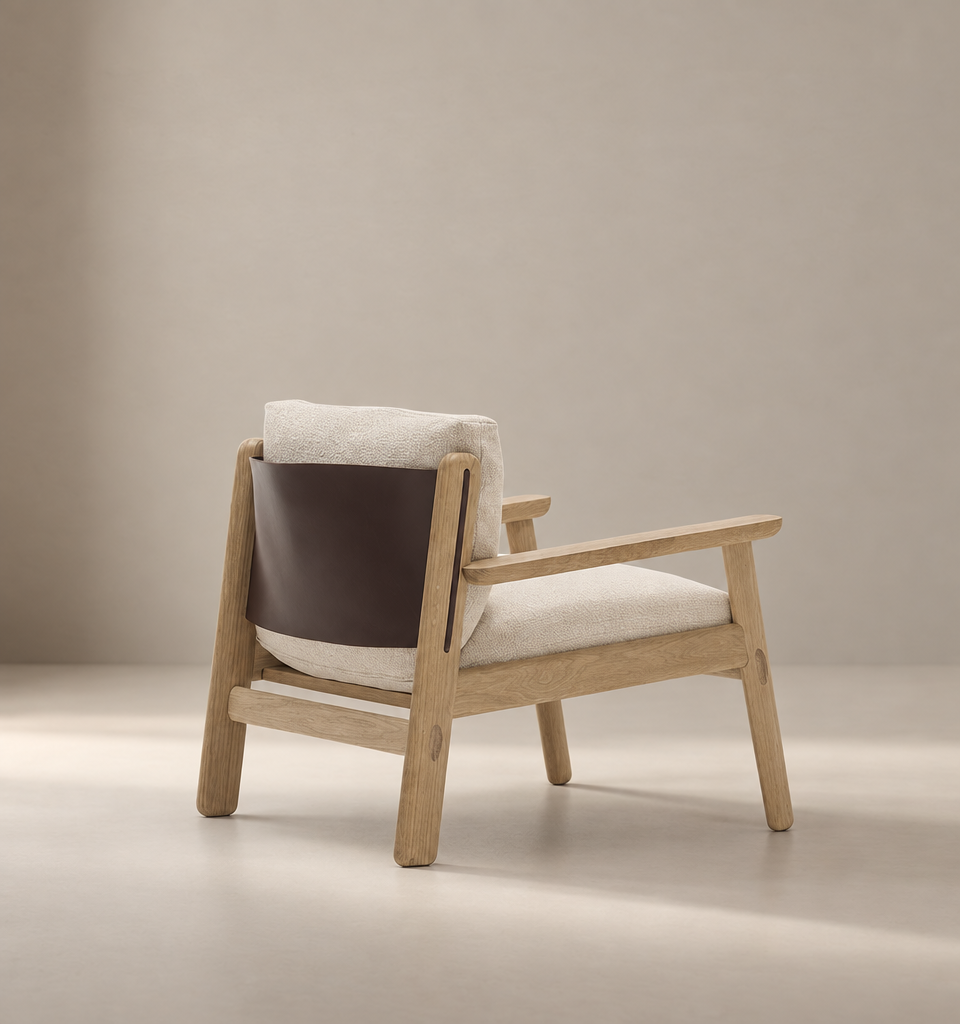 Introducing the Wren Lounge Chair | Fabric by Wooden Stories—a modern armchair crafted from solid walnut and inspired by Danish design. This chair features light beige fabric cushions and a dark brown leather backrest, beautifully set against a neutral, softly lit background.