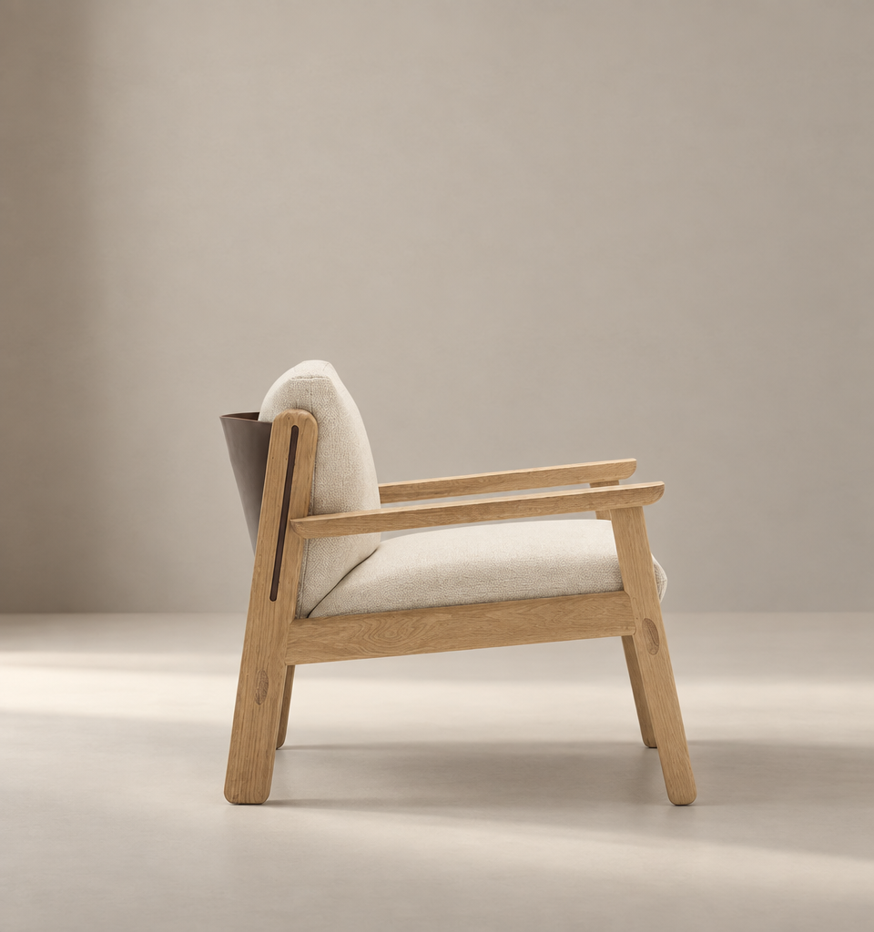 The Wren Lounge Chair | Fabric by Wooden Stories is displayed in side profile against a softly lit, neutral background. Crafted from solid walnut, this modern wooden armchair features beige upholstery, clean lines, and a minimalist, Scandinavian-inspired silhouette reminiscent of classic Danish design.