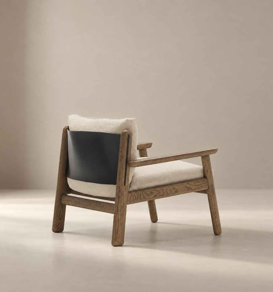 The Wren Lounge Chair | Fabric by Wooden Stories is a modern wooden lounge chair inspired by Danish design, crafted from solid walnut and featuring light beige fabric cushions with a black leather backrest, displayed against a softly lit, plain beige background.