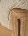 Close-up of the Wren Lounge Chair | Fabric by Wooden Stories, featuring a smooth solid walnut wood leg and a beige woven fabric cushion. The visible wood grain and soft upholstery showcase the materials and craftsmanship characteristic of Danish furniture design.