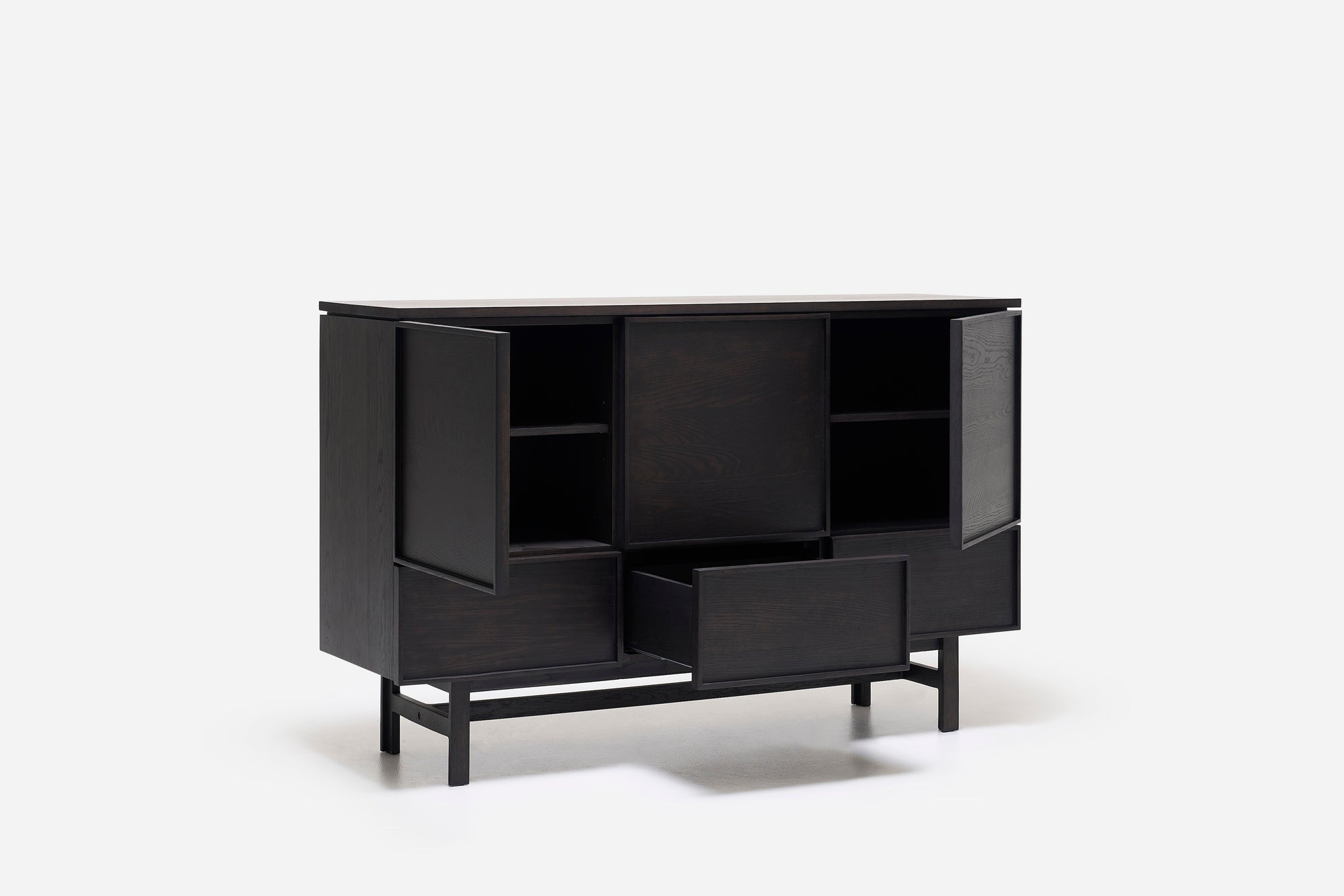 The Yorke Highboard by Wooden Stories features modern Scandinavian design with dark wood, angled legs, two doors revealing shelves, and two partially open drawers, all set against a plain white background.
