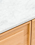 Close-up of a white marble stone top with subtle gray veining on the Wooden Stories Yorke Sideboard, featuring light-colored cabinets and a simple, modern design inspired by gentle Danish lines.