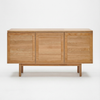 The Yorke Sideboard by Wooden Stories is a minimalist solid oak piece with three doors, a light natural finish, and Scandinavian design. It stands on four sturdy legs and is pictured against a plain white background.