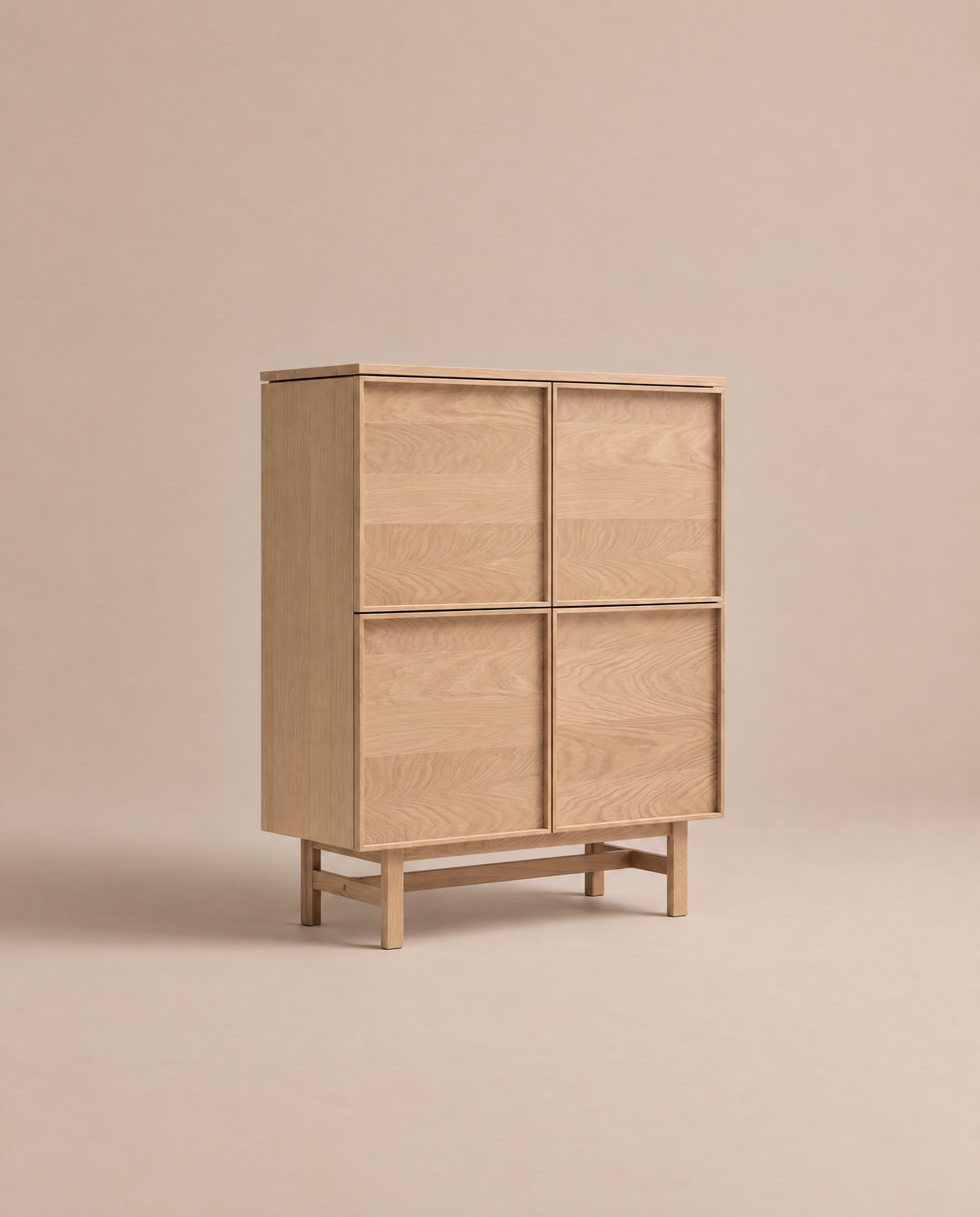 The Yorke Highboard by Wooden Stories features a light oak finish with four square doors and stands on a minimalist wooden frame. Isolated against a neutral beige background, this piece highlights its clean, modern aesthetic and visible wood grain, evoking classic Danish highboard style and Scandinavian design.
