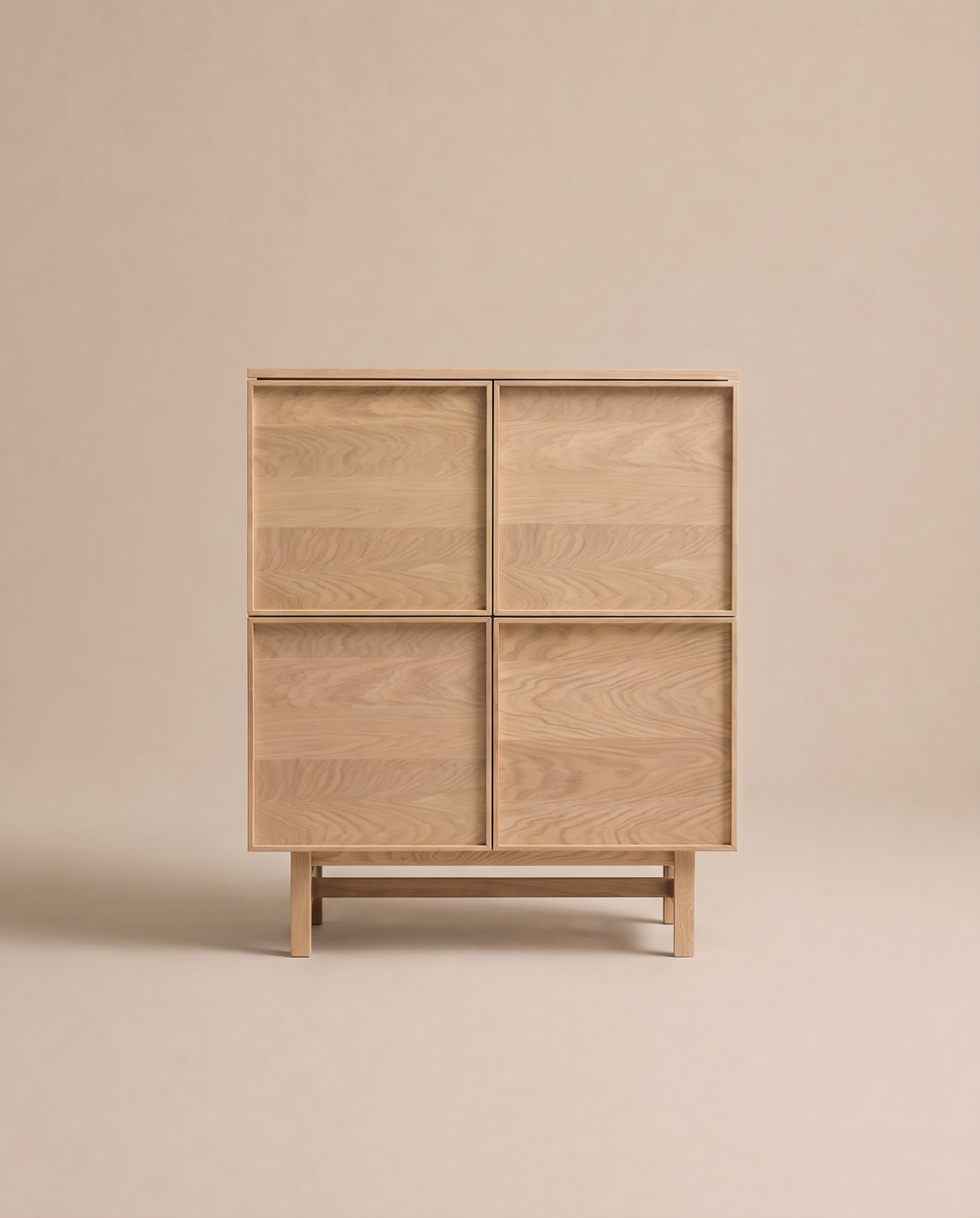 The Yorke Highboard by Wooden Stories stands on short legs against a plain beige background, showcasing the elegance of Scandinavian design with its light wood construction and four square doors adorned with subtle wood grain patterns.