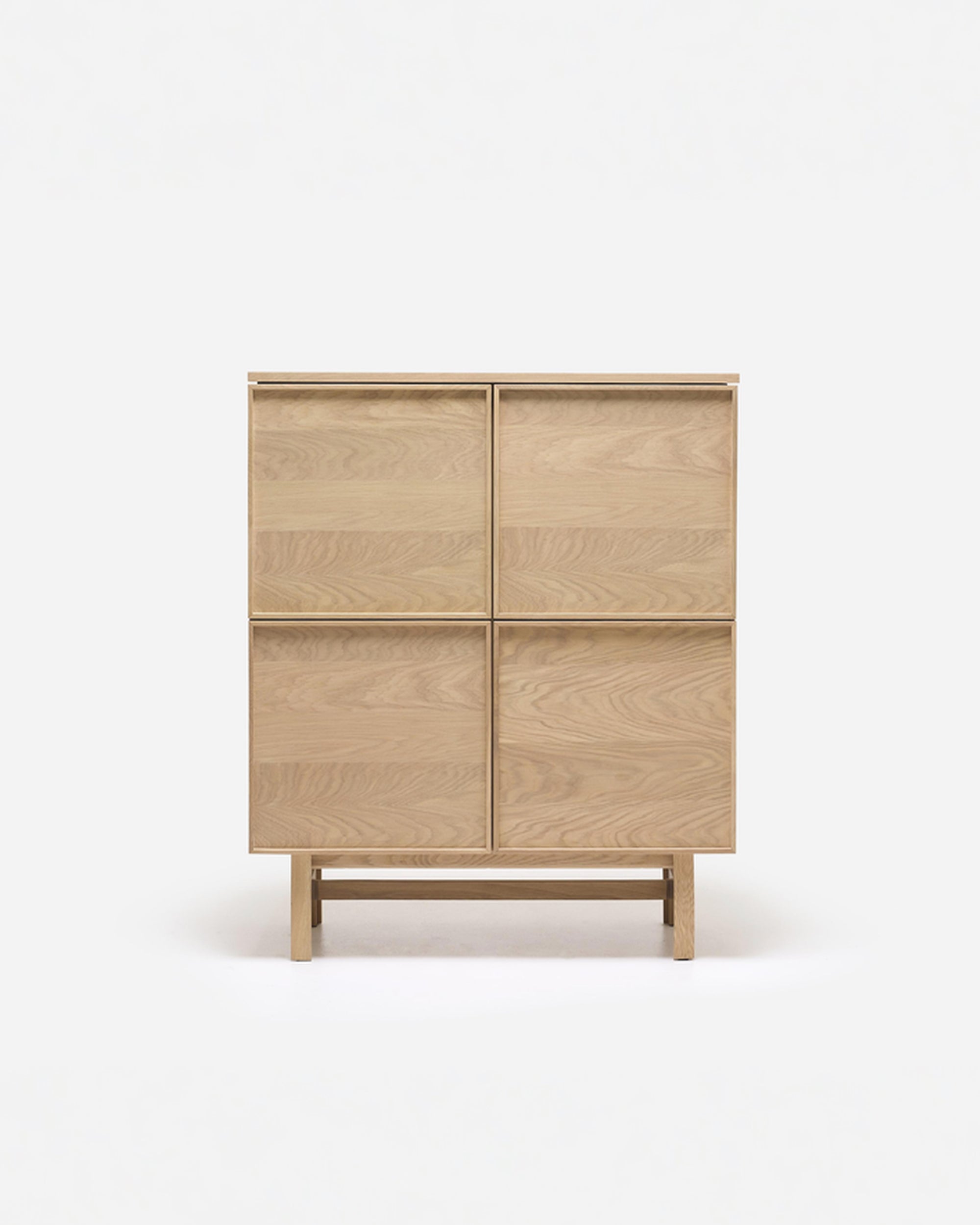 The Yorke Highboard by Wooden Stories is a light wood Scandinavian storage cabinet featuring four panel doors and a simple rectangular design, standing on a matching wooden base against a plain white background.
