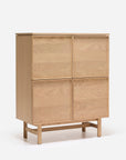 The Wooden Stories Yorke Highboard is a Scandinavian-inspired light wood cabinet with four square doors, a minimalist profile, and short legs connected by a horizontal support bar, shown against a plain white background.