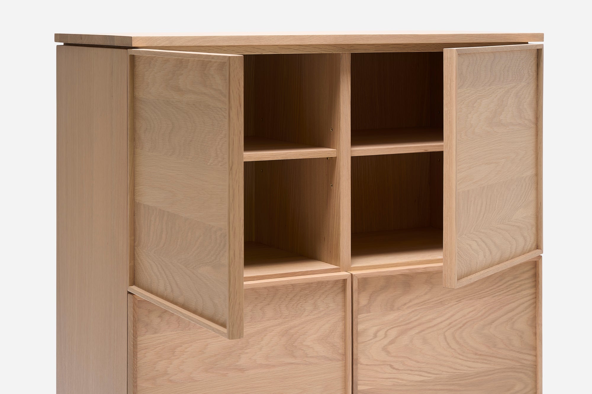 The Yorke Highboard by Wooden Stories is a wooden cabinet with four square compartments, two open doors, simple clean lines, and a natural light finish—capturing Scandinavian design against a plain backdrop.