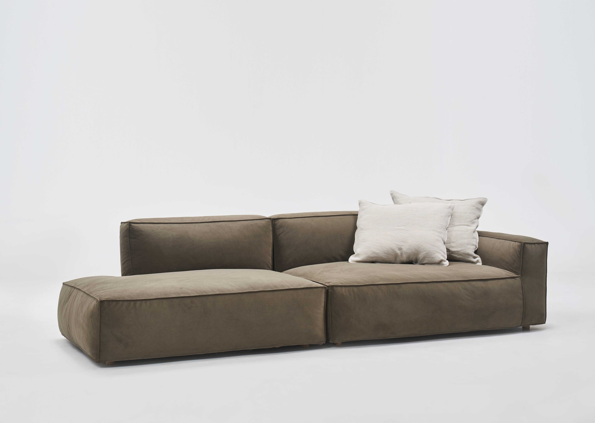 The Baker Modular Sofa | Fabric • M2 by Wooden Stories is a modern olive green sofa with a low backrest and two light beige throw pillows, shown against a plain white background.