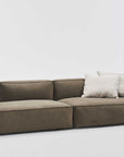 The Baker Modular Sofa | Fabric • M2 by Wooden Stories is a modern olive green sofa with a low backrest and two light beige throw pillows, shown against a plain white background.