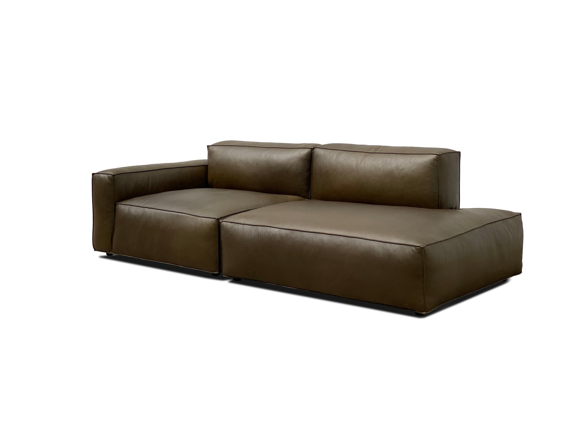 The Baker Modular Sofa | Leather • M1 by Wooden Stories is a modern, dark brown sectional with wide seats, low armrests, and plush back cushions. Its clean lines and contemporary style stand out against a white background.