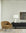 A modern living room with a vintage vibe features the Ethnicraft Barrow Lounge Chair in Ginger, a black sideboard with a white lamp, glass, and magazines, abstract wall art on light walls, light wood flooring, and sheer curtains.