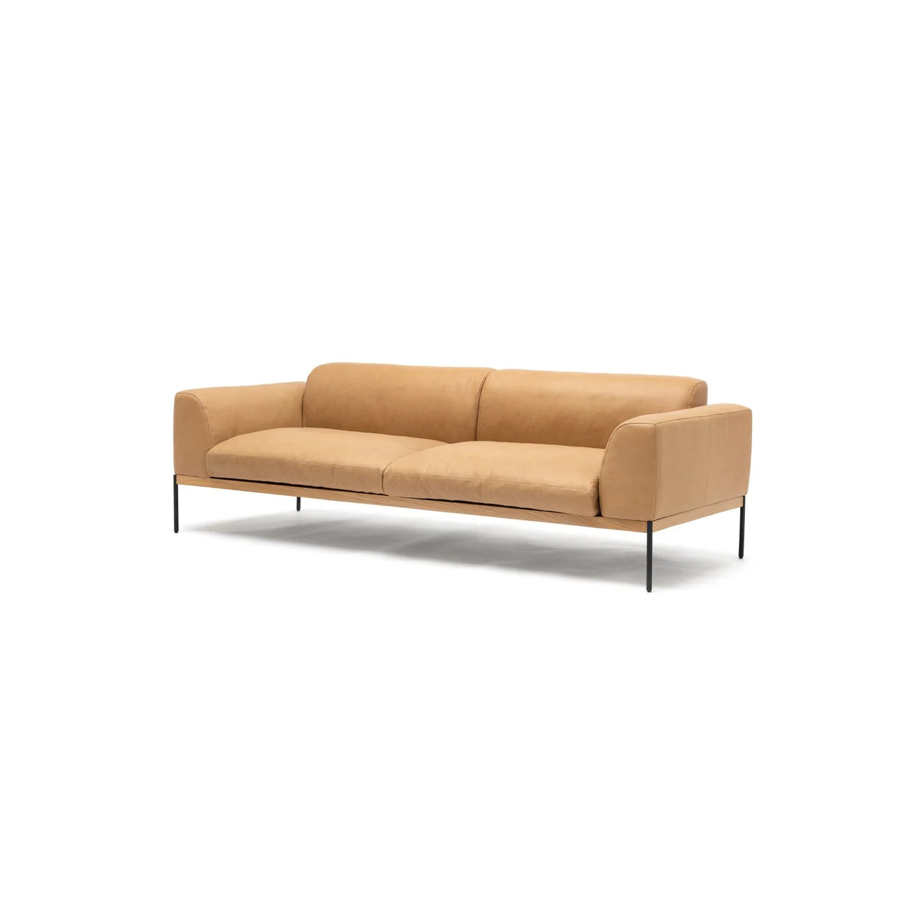 The Department Sofa 93" by Wooden Stories features modern Danish lines, tan leather upholstery, thin black metal legs, and low armrests, displayed on an upholstered platform against a plain white background.