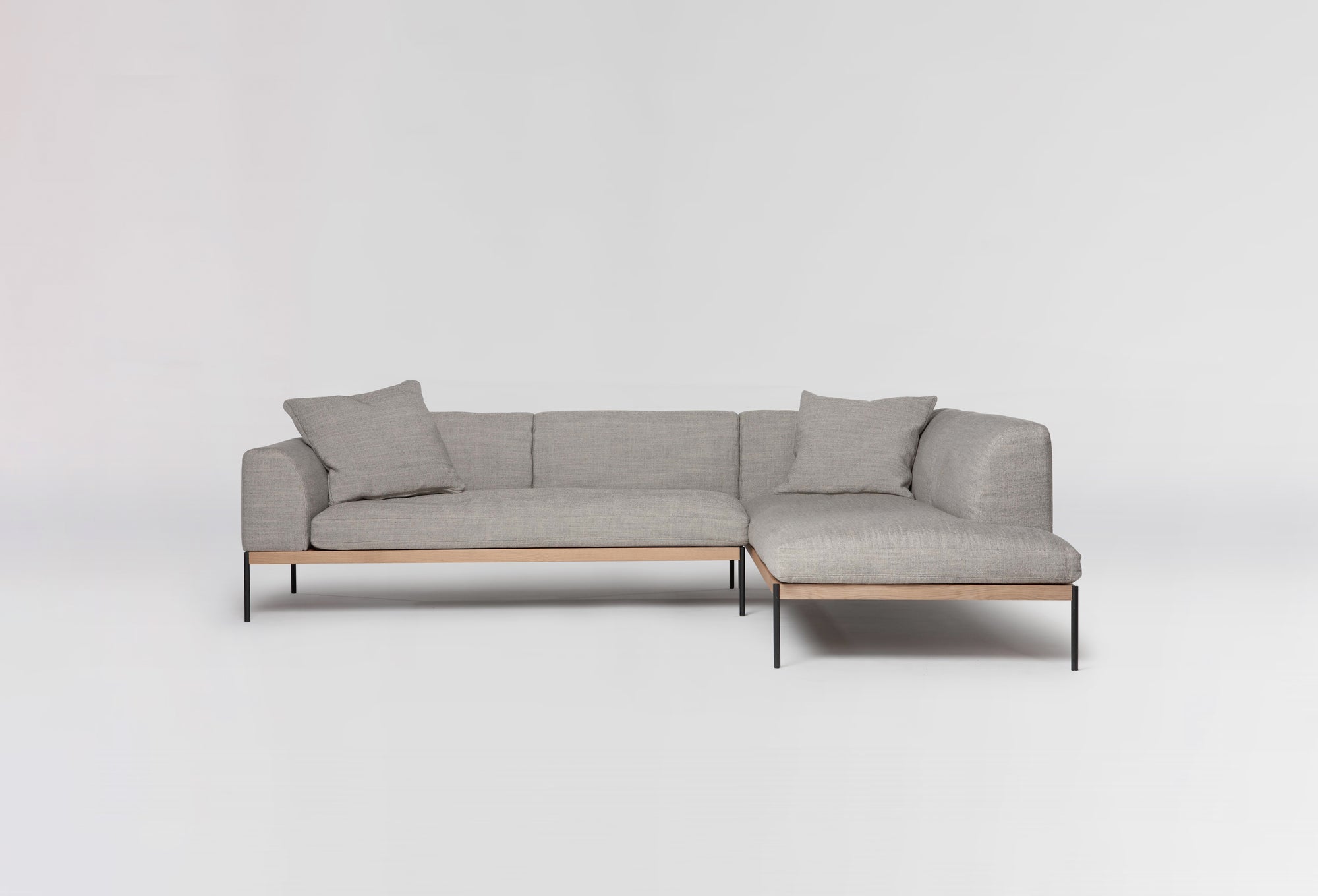 The Wooden Stories Department Modular Sofa | Fabric • M6 Right features light gray upholstery, thin black metal legs, and an FSC-certified oak base with three matching cushions, shown against a plain white background.