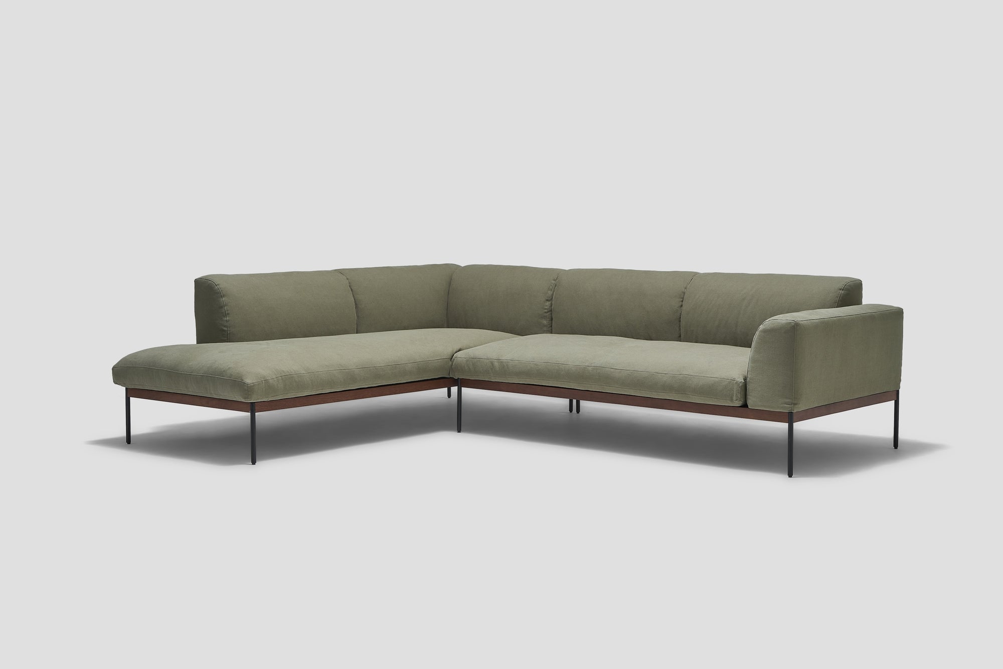 The Wooden Stories Department Modular Sofa | Fabric • M6 Left features olive green cushions, slim black metal legs, and a low FSC-certified oak base, showcased against a light gray background.