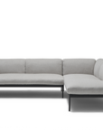 The Department Modular Sofa | Fabric · M6 Right by Wooden Stories is a modern, light gray L-shaped sectional with a solid wood base, slim black metal legs, tufted seats, plush backrests, and Danish-inspired design against a white background.