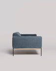 The Department Sofa 81" by Wooden Stories is a modern blue fabric sofa with Danish-inspired lines, slim black legs, and a solid wood plinth accent underneath, shown from the side against a plain light background.
