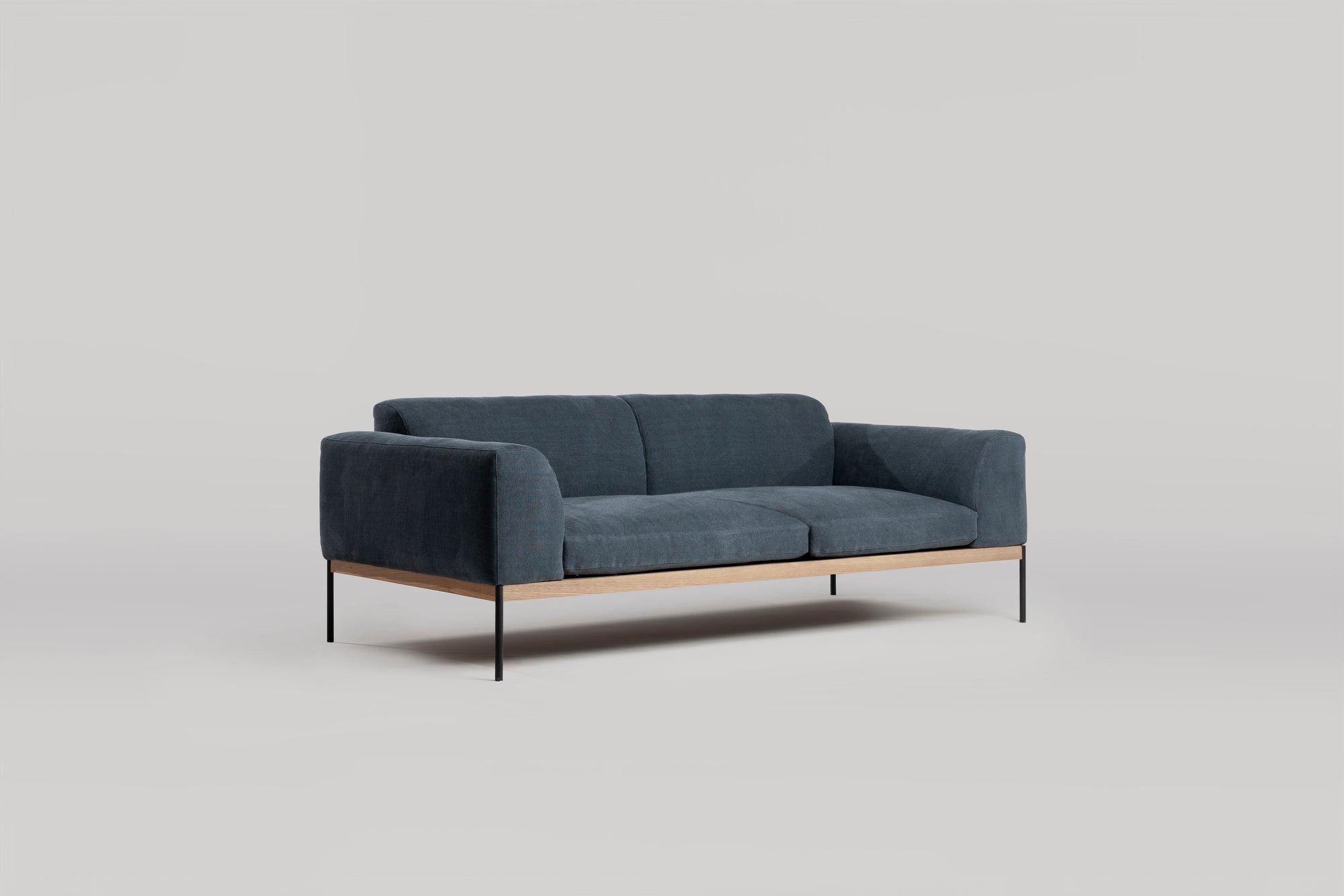The Wooden Stories Department Sofa 81" | Fabric features a modern dark blue design with Danish lines, a solid wood plinth base, and slim black metal legs, shown against a plain light gray background.