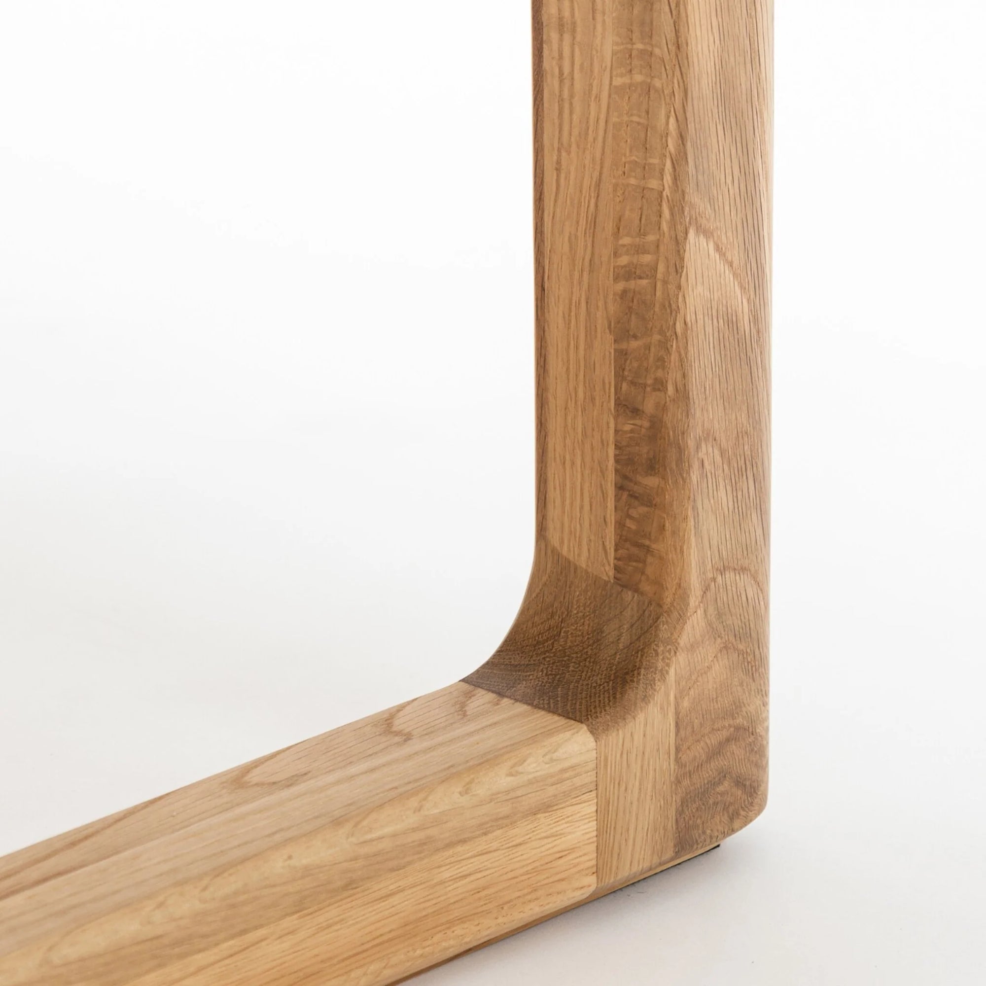 Close-up of the corner joint of the Wooden Stories Hover Dining Table in Light Oak, featuring smooth, light-colored wood with visible grain and Danish lines against a plain white background.