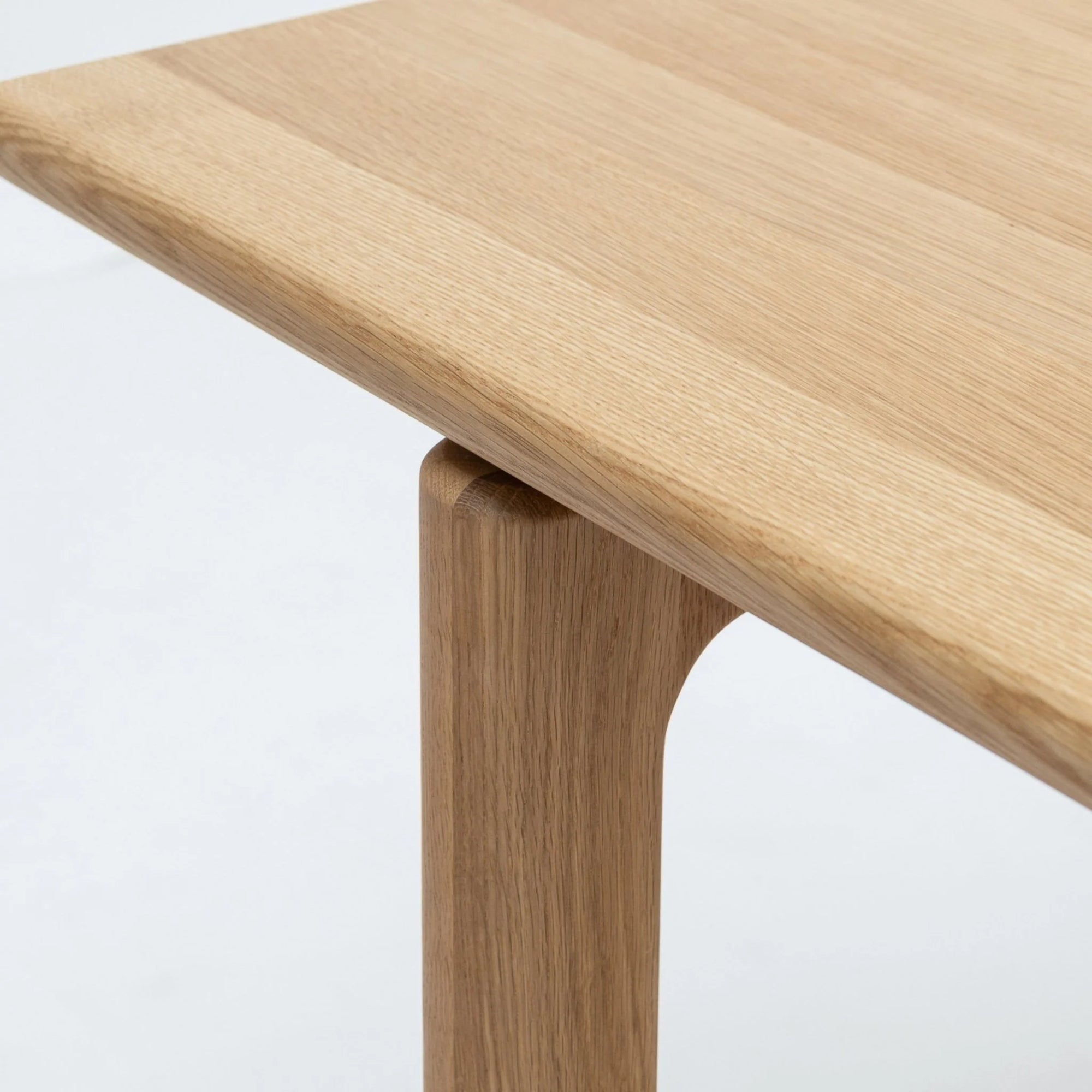A close-up of the Wooden Stories Hover Dining Table | Light Oak features its smooth, rounded corner and natural wood grain, showcasing clean Danish-inspired lines and minimalist design.