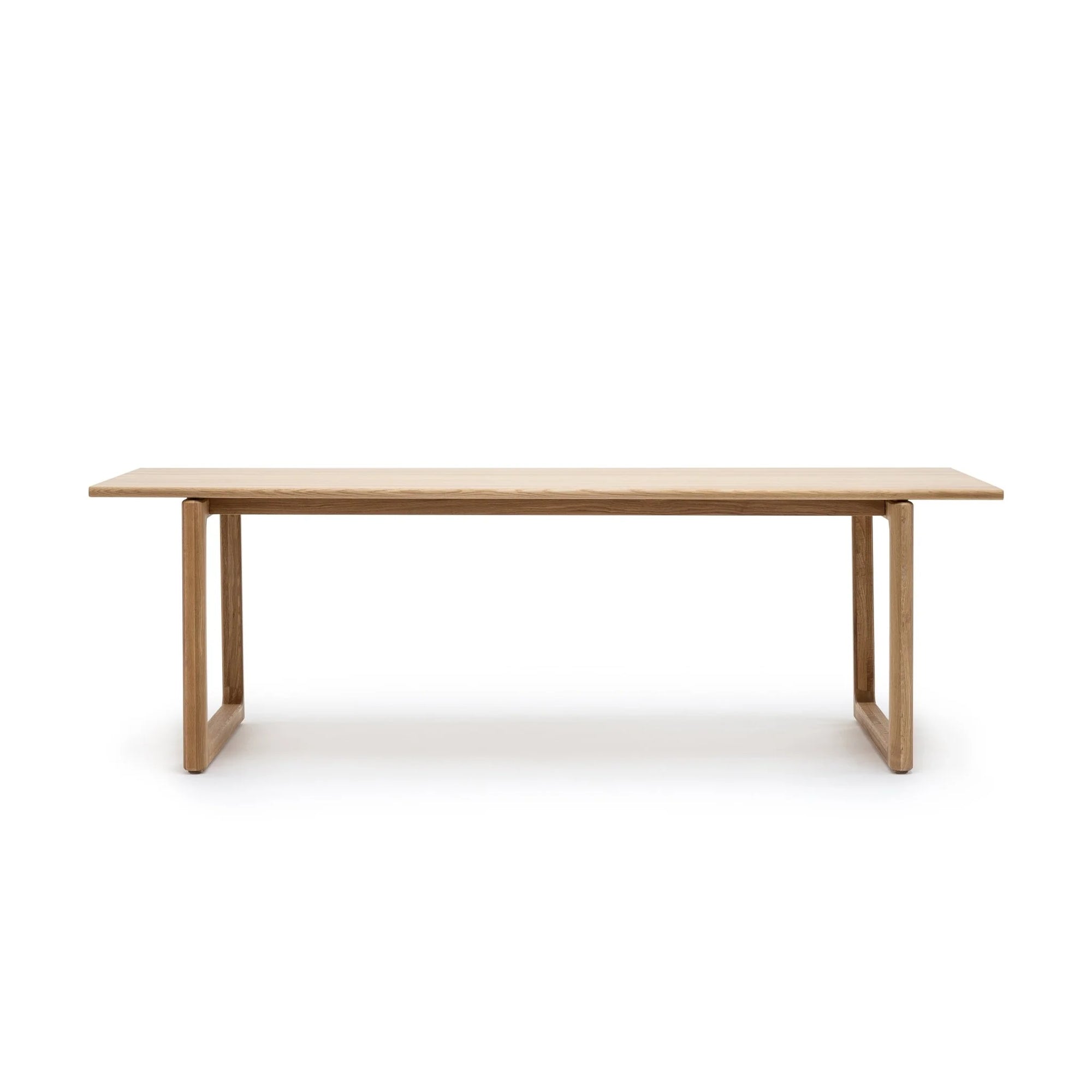 The Hover Dining Table by Wooden Stories is a minimalist, rectangular light oak table with sleek Danish lines and two sturdy end supports. Perfect for dining rooms, it's photographed against a plain white background.