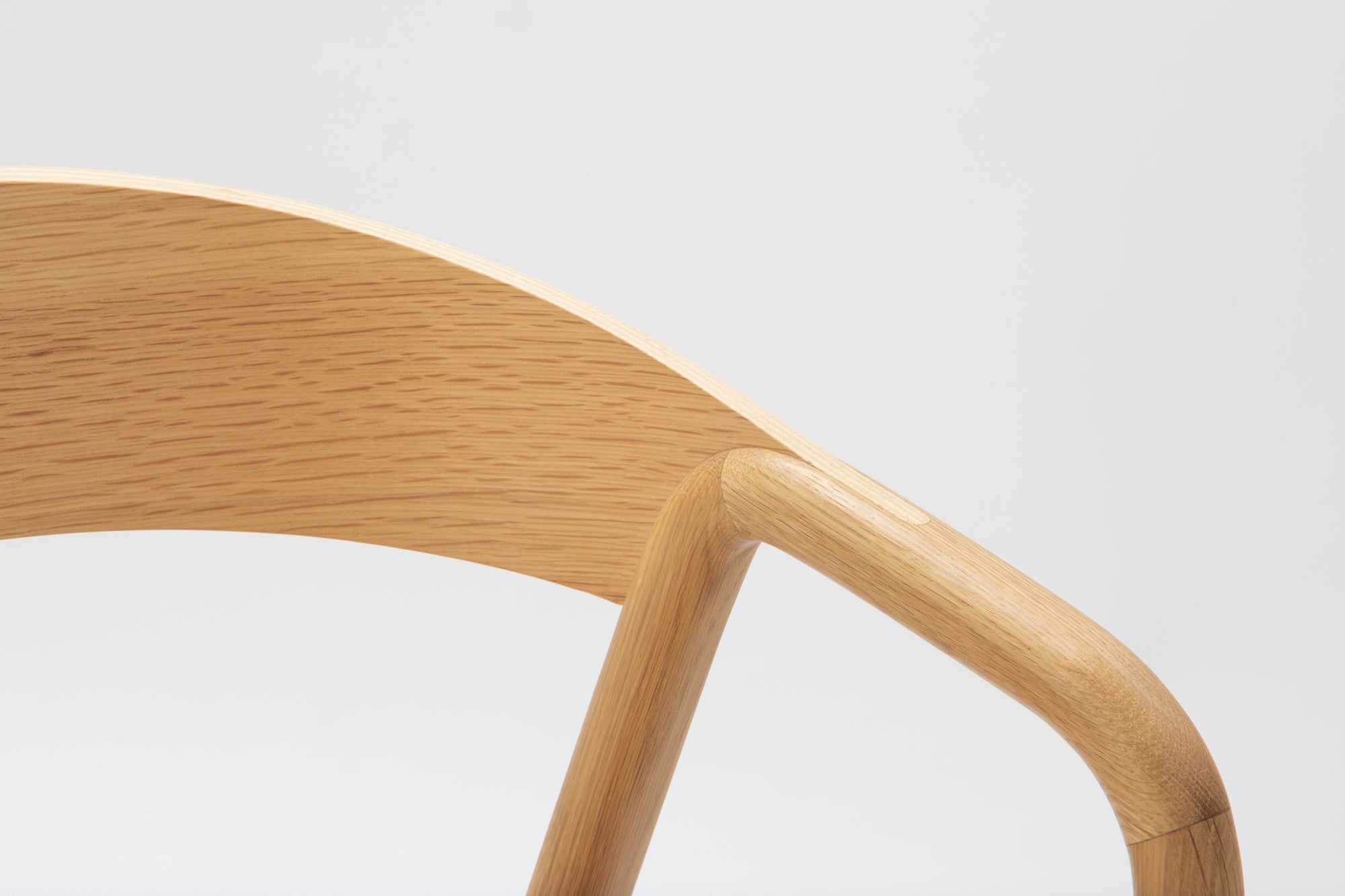 Close-up of the Wooden Stories Inlay Dining Chair | Light Oak, featuring a smooth plywood backrest and angled solid wood arms in a light natural oak finish, set against a plain white background.