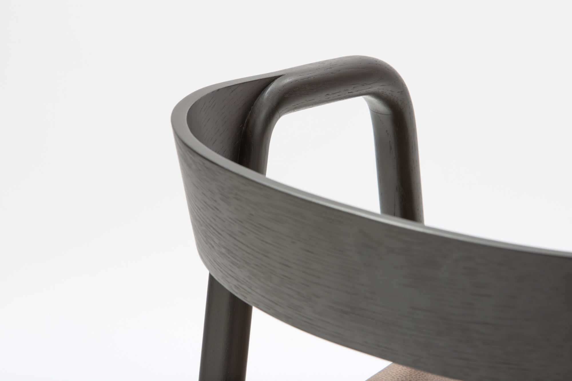 Close-up of the backrest and upper frame of the Wooden Stories Inlay Dining Chair in Black Oak and Leather, showing smooth curves and a plywood backrest against a plain white background.
