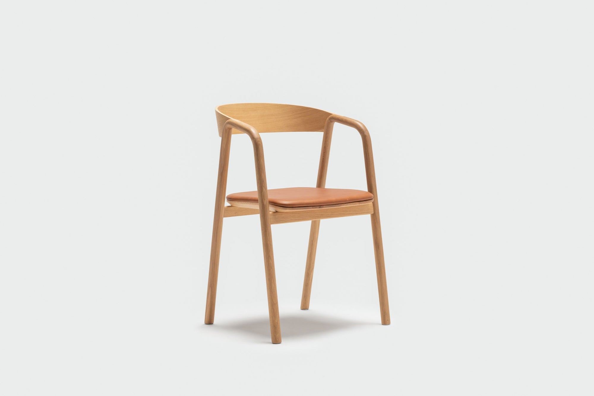 The Wooden Stories Inlay Dining Chair features a curved plywood backrest and arms in light oak, plus a light brown leather upholstered seat, shown against a plain white background.