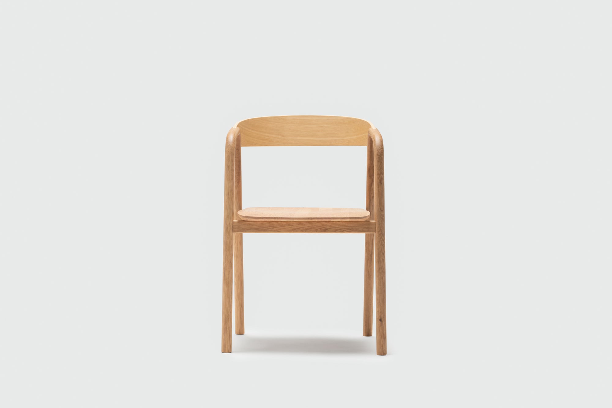 The Wooden Stories Inlay Dining Chair in Light Oak features a simple, modern design with a curved plywood backrest and straight legs, shown against a plain white background.