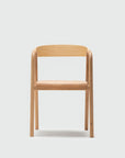 The Wooden Stories Inlay Dining Chair in Light Oak features a simple, modern design with a curved plywood backrest and straight legs, shown against a plain white background.