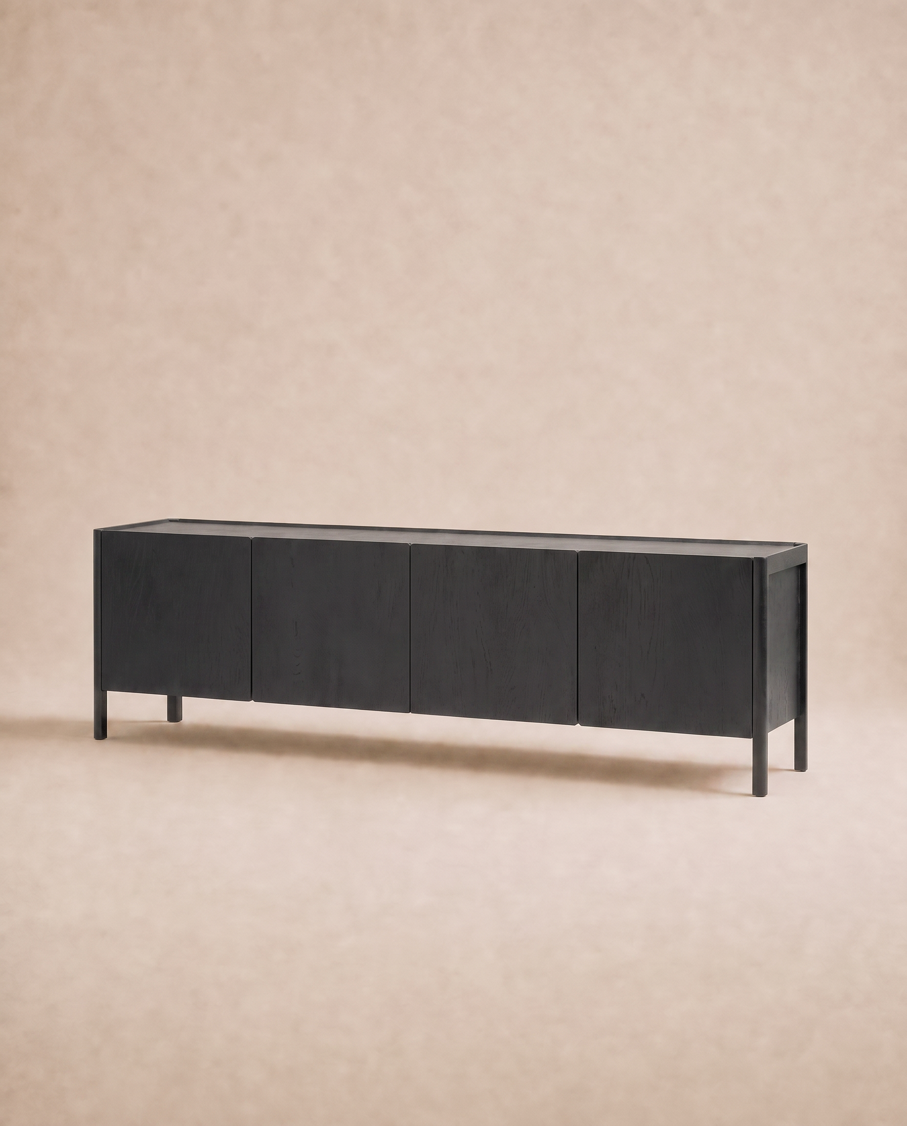 The Nell Sideboard | Black Oak by Wooden Stories features a minimalist design with four doors and clean lines, embodying Scandinavian style and set against a neutral beige background.