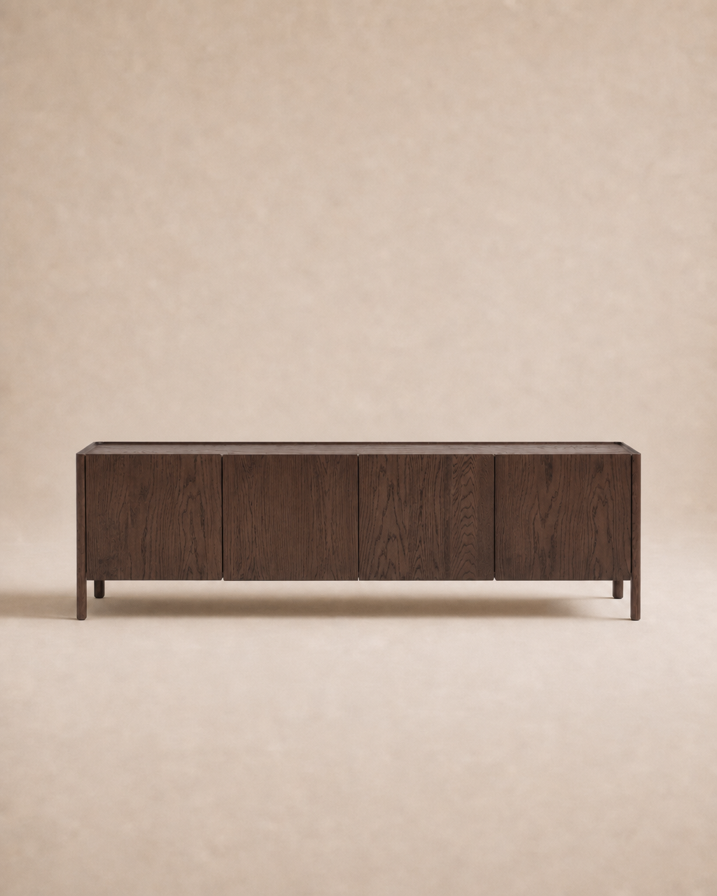The Wooden Stories Nell Sideboard | Espresso Oak is a rectangular, dark wood sideboard featuring four cabinet doors and short legs, crafted from solid oak in an understated Scandinavian design, set against a plain beige background.