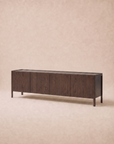 A long, rectangular Nell Sideboard in Espresso Oak by Wooden Stories, featuring four doors and simple legs that embody Scandinavian design, is set against a soft beige background.