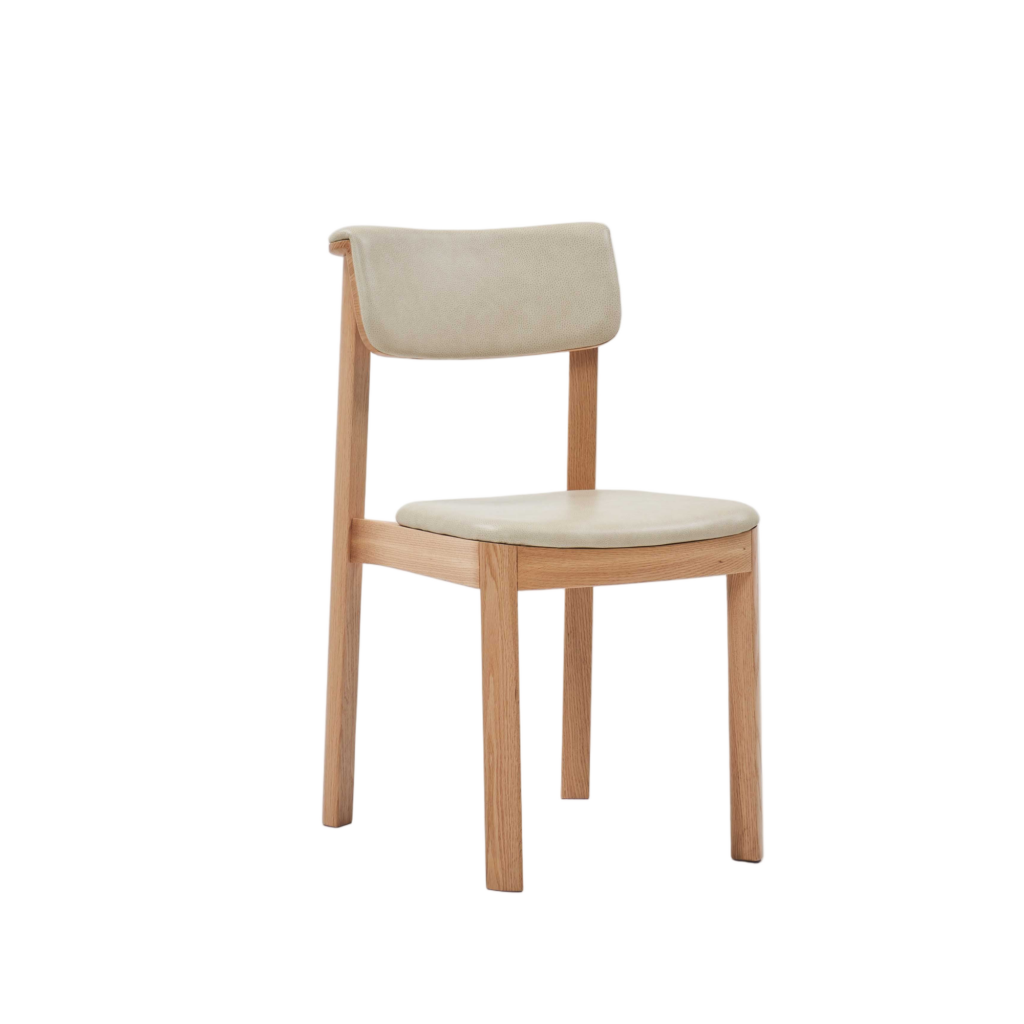 The Noki Dining Chair by Wooden Stories features a modern light oak frame with a matching curved back and beige leather seat—perfect for contract grade interiors.