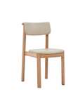 The Noki Dining Chair by Wooden Stories features a modern light oak frame with a matching curved back and beige leather seat—perfect for contract grade interiors.