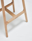 Close-up of the Odd Counter Stool by Wooden Stories, featuring light oak legs with a leather seat. The smooth, rounded edges and visible wood grain reflect true Danish design style, shown on a white background.