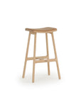 The Odd Counter Stool by Wooden Stories features a light oak frame, four legs with a footrest, and a curved leather seat in classic Danish style—all set against a plain white background.