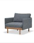The Wooden Stories Pensive Lounge Chair | Fabric features grey upholstered cushions, Danish-inspired lines, square armrests, and wooden legs, set against a plain white background.
