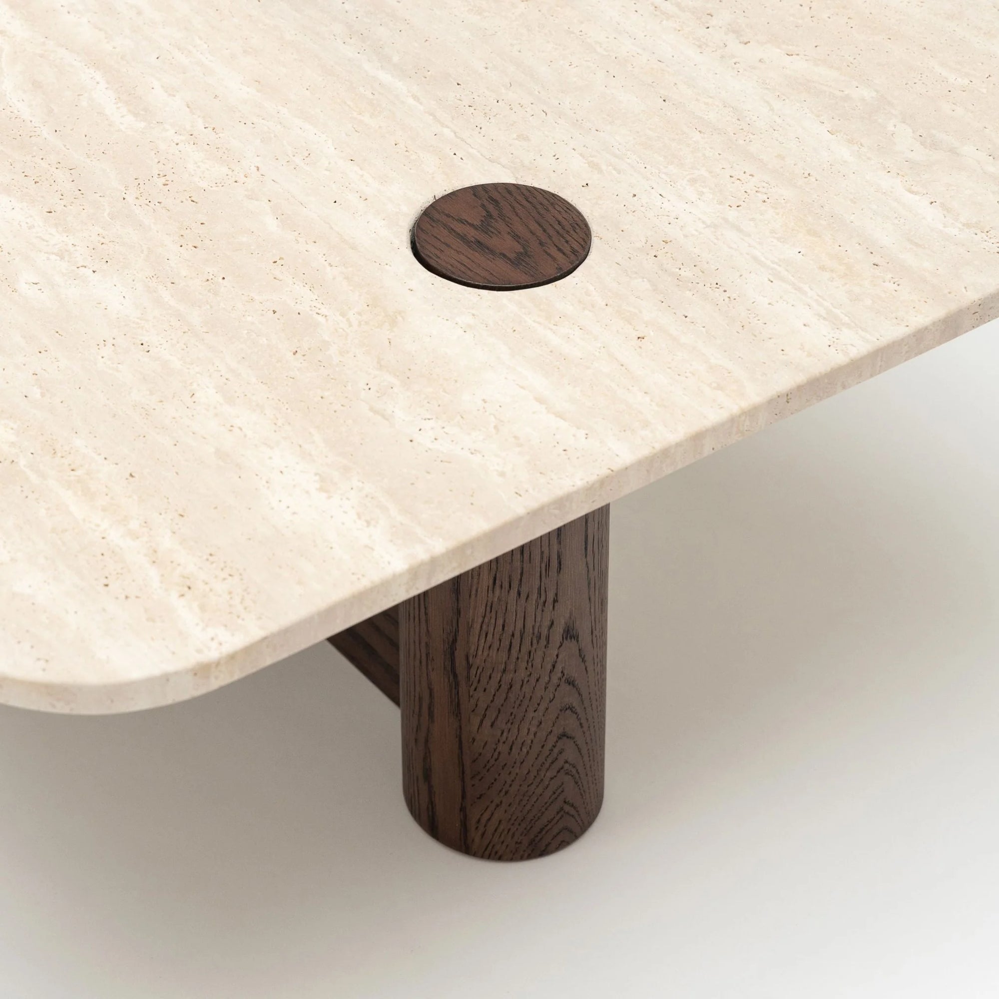 A close-up of the Pivot Coffee Table | Rectangular by Wooden Stories, showcasing its light marble surface with rounded edges and a circular solid wood accent and leg, set against a plain light background.